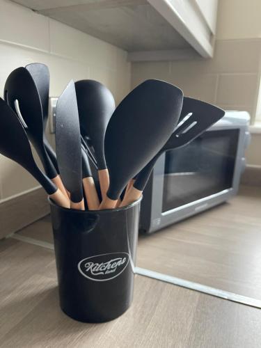 Ein schwarzer Becher, gefüllt mit Küchenutensilien, neben einem Ofen in der Unterkunft 4 bed house perfect for contractors in Coseley