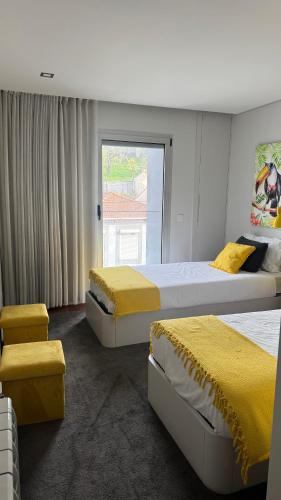 two beds in a bedroom with yellow sheets and a window at Casa Douro in Valbom