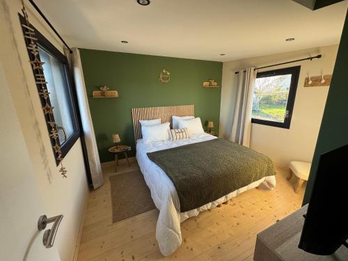 a bedroom with a bed and a green wall at Lodges des Pontons - Cap Sud - vue mer in Saint-Côme-de-Fresné