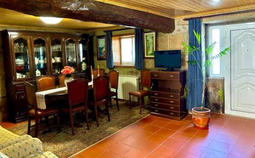 een eetkamer met een tafel, stoelen en een televisie bij Casa 3 Irmãs in Vale de Anta