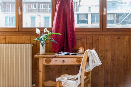 ein hölzernes Zimmer mit einem Tisch, auf dem eine Pflanze stand, und einem Fenster in der Unterkunft Hôtel Vallée Blanche in Chamonix-Mont-Blanc