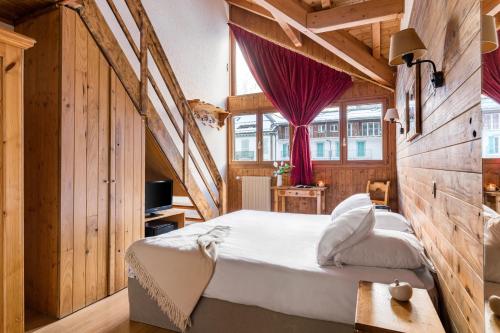 ein Schlafzimmer mit einem großen Bett in einem Zimmer mit Holzwänden in der Unterkunft Hôtel Vallée Blanche in Chamonix-Mont-Blanc