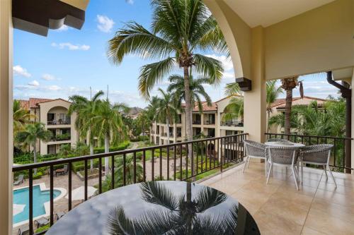 a balcony with a table and chairs and palm trees at Elegant Condo in High-End Resort Community with Pool and Beach Club Access in Coco