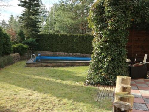 a swimming pool in a yard with a hedge at Apartment mit Pool by Interhome in Bad Schmiedeberg