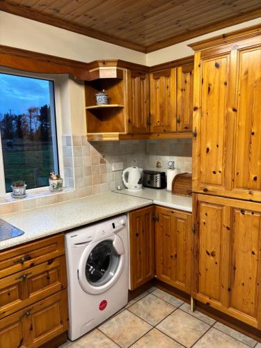 a washing machine in a kitchen with wooden cabinets at Sonnys Rest in Ardara