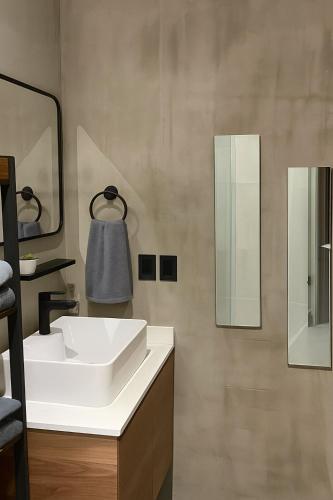 a bathroom with a white sink and two mirrors at Stylish Condo Steps to Beach & Malecón in Mazatlán