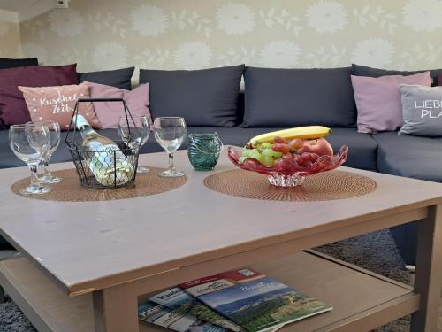 a coffee table with a bowl of fruit and wine glasses at Apartment FeWo Steinbeisser by Interhome in Arrach