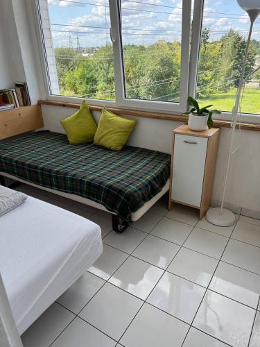 a room with two beds and a bench with two windows at Kaunas Homestay in Kaunas