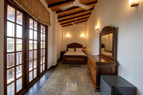 een slaapkamer met een bed, een spiegel en ramen bij Epic Unawatuna in Unawatuna