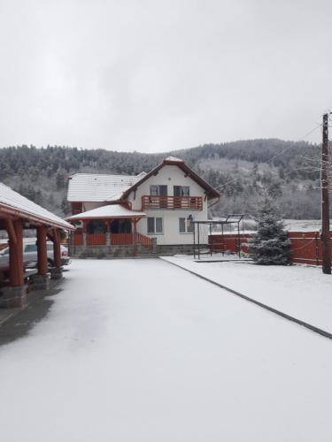 een gebouw met sneeuw op de grond ervoor bij Dió vendégház in Praid