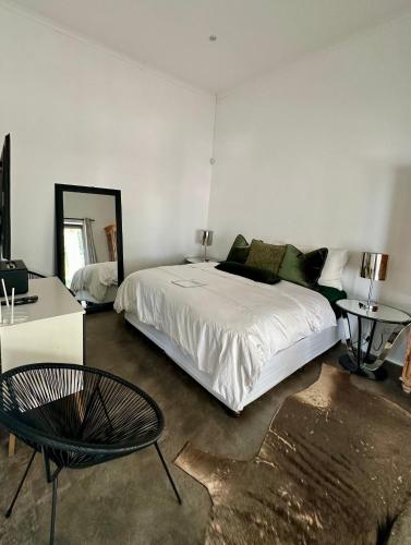a bedroom with a bed and a table and a mirror at White House Cottage in Koekoeb