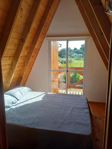 a bedroom with a bed and a large window at Cabañas Amapola del 66 in Miramar