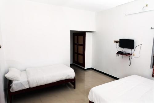 a room with two beds and a tv on the wall at Aroma Resort Hill Palace in Kolli Hills