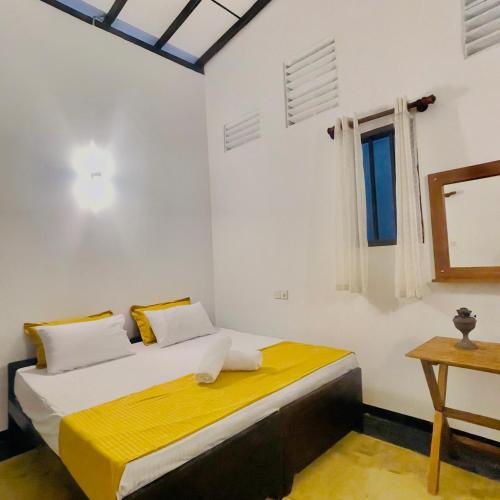 a bedroom with a bed and a window and a table at Villa Senu in Ambalangoda