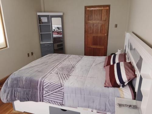 ein Schlafzimmer mit einem großen Bett und einer Holztür in der Unterkunft Central Stay Departamentos III in Oruro