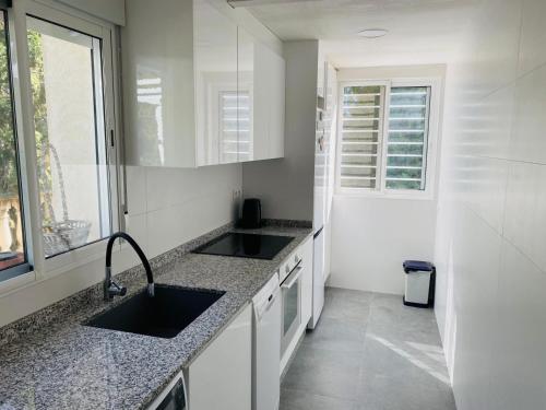 a white kitchen with two sinks and a window at La Casa del bosque in Valencia