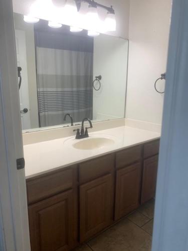 un bagno con un lavandino e un grande specchio di Military PCS Training RBAFB FSAB a San Antonio