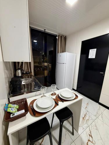 una cucina con tavolo con 2 sedie e frigorifero di Loft 04 na Praia Brava a Itajaí