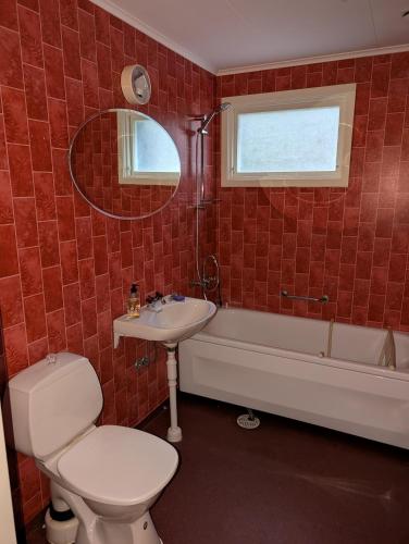 a bathroom with a toilet and a sink and a tub at Lägenhet nära naturen Pralinette BB in Nykroppa