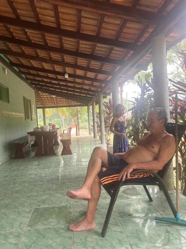 a man sitting in a chair with a child in the background at RECANTO DO SABIÁ in Carolina