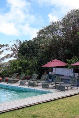 a row of chairs and umbrellas next to a swimming pool at Pousada Vila Corada in Pipa