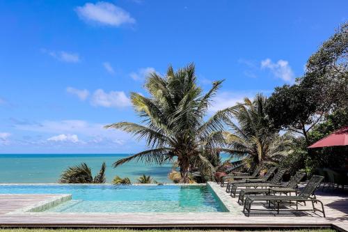 une piscine avec des chaises et l'océan en arrière-plan dans l'établissement Pousada Vila Corada, à Pipa