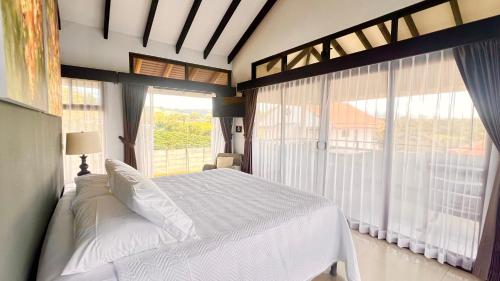 una camera da letto con un letto bianco e ampie finestre di Ruta Verde BB a Tambor