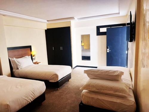 a hotel room with two beds and a tv at Hotel redouane in Marrakech