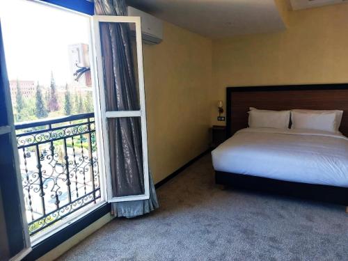 a bedroom with a bed and a large window at Hotel redouane in Marrakech