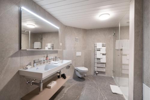 a bathroom with a sink and a toilet and a mirror at Hotel Grindelwalderhof in Grindelwald
