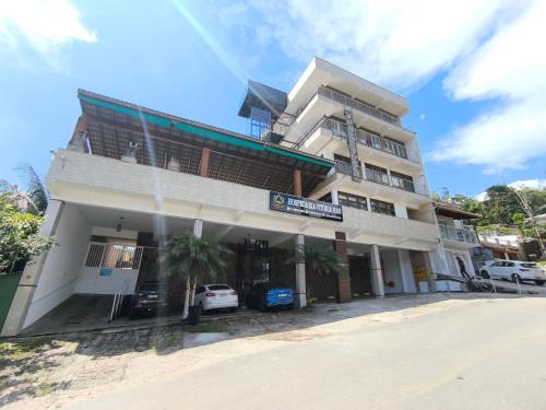 een hoog gebouw met auto's ervoor geparkeerd bij Hospedaria Vitória Mar in Ubatuba