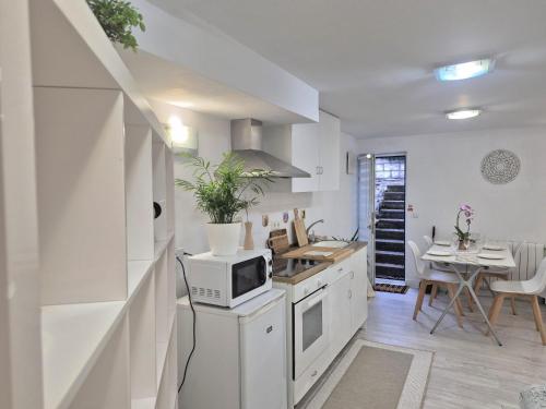 een witte keuken met een magnetron en een tafel bij Basement studio in hosts house with private terrace and BBQ Ideal for The camino in Zizur Mayor