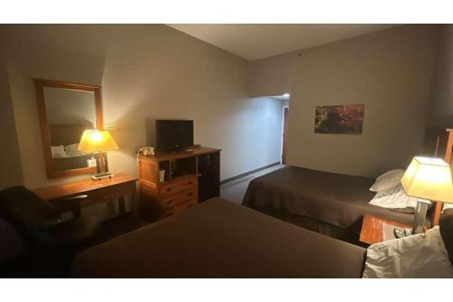 a hotel room with a bed and a desk with a mirror at Pleasant Night Inn Carthage Near Fort Drum in West Carthage