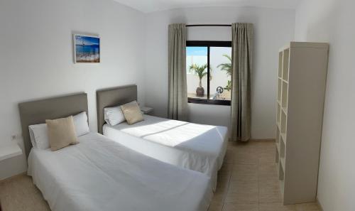 two beds in a room with a window at CuevaBlanca in Güime