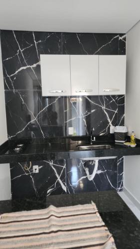 a kitchen with a black marble counter and white cabinets at kitnets Praia Super in Cumuruxatiba