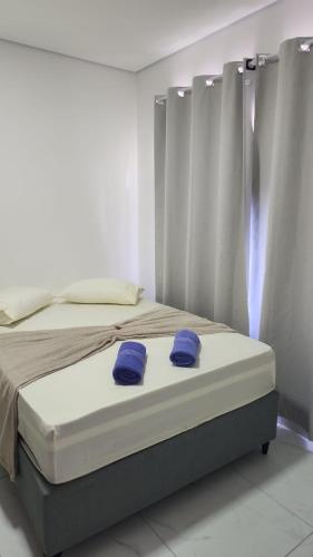 a bed with two blue pillows on top of it at kitnets Praia Super in Cumuruxatiba