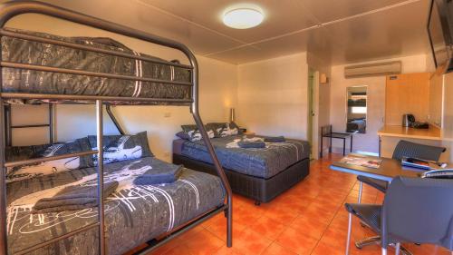 a bedroom with two bunk beds and a desk at Halls Creek Motel in Halls Creek