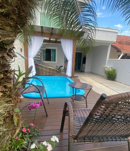 een terras met een tafel en stoelen en een zwembad bij Casa com piscina in Bombinhas