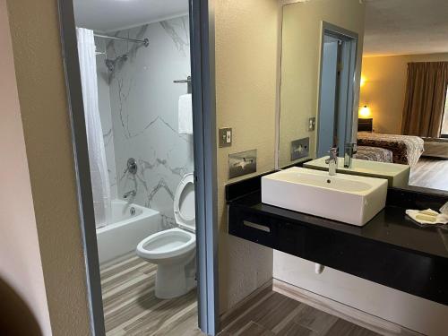 a bathroom with a sink and a toilet and a mirror at Brookwood Inn - Extended Stay in Charlotte