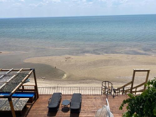 a deck with a beach with two chairs and a playground at Water Front Beach House - 3BR w BBQ & Sunset in Fort Erie