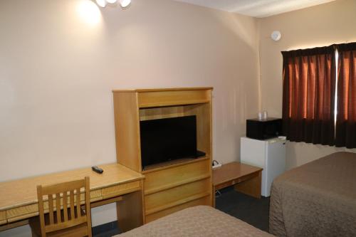 a hotel room with a desk with a television and a bed at Nights Inn Motel in Thunder Bay