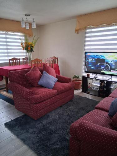 a living room with two red couches and a television at Búho Real Cityhouse in El Cerrillo
