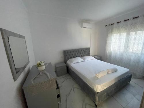 una camera da letto bianca con un letto e uno specchio di Casa Mia a Vlorë