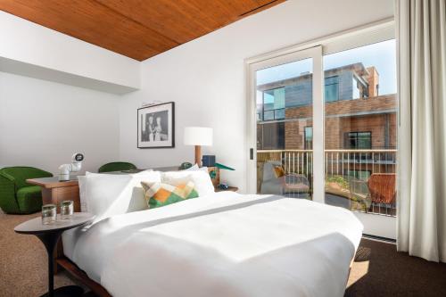 a bedroom with a large white bed and a large window at Hotel Magdalena in Austin