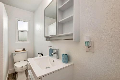 a white bathroom with a toilet and a sink at The Cozy Cove I 3 min to Beach in Bradenton