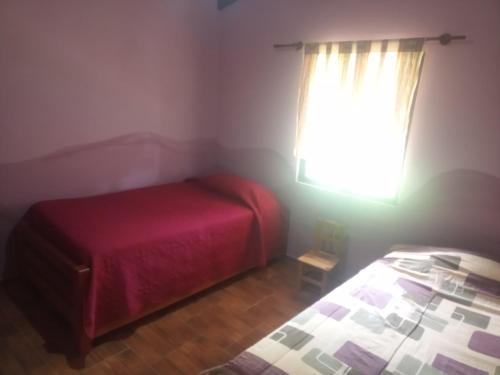 una camera da letto con un letto rosso e una finestra di Wasi a Samaipata