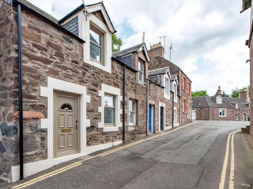 a row of brick houses on an empty street at Meadow Hill Cottage with Private Garden, Crieff in Crieff