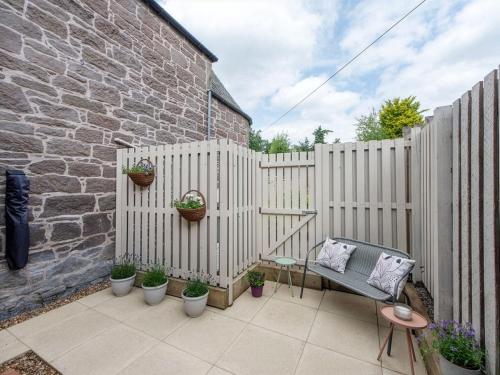 a patio with a fence with potted plants and a chair at Meadow Hill Cottage with Private Garden, Crieff in Crieff
