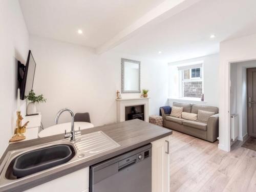 a kitchen with a sink and a living room at Meadow Hill Cottage with Private Garden, Crieff in Crieff