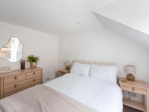a white bedroom with a bed and two night stands at Meadow Hill Cottage with Private Garden, Crieff in Crieff